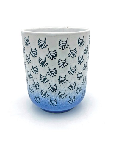 Close up of a white & blue mug with dark blue leaf patterns and a blue gradient at the bottom. Close up of a white & blue mug with dark blue leaf patterns and a blue gradient at the bottom.