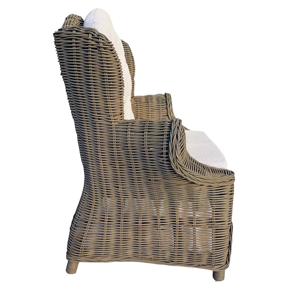 Zijaanzicht van een rotan kinderstoel met afgeronde armleuningen en een hoge rug. Zijaanzicht van een rotan kinderstoel met afgeronde armleuningen en een hoge rug.