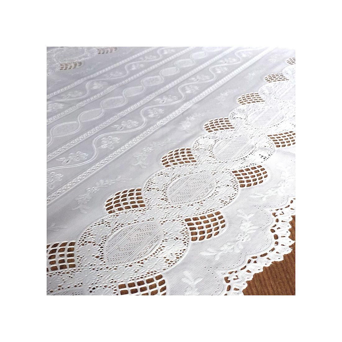 Close up detail of a white table runner made from vinyl with lace details and scalloped edges.