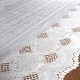 Close up detail of a white table runner made from vinyl with lace details and scalloped edges.