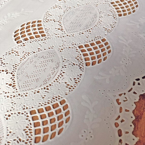 Close up detail of a white table runner made from vinyl with lace details.