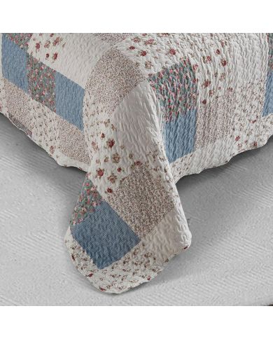 Detail of a floral bedspread showcasing blue and white patchwork, vermicelli stitching and scalloped edging. Detail of a floral bedspread showcasing blue and white patchwork, vermicelli stitching and scalloped edging.