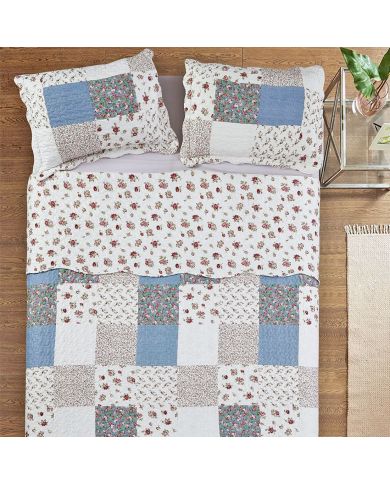 Bovenaanzicht van een bed sprei bloemen motief op een bed, aangevuld met bijpassende sierkussens.