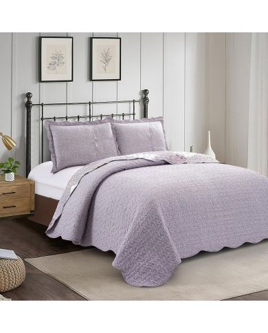 Showcasing the reverse design of Lavender Dream quilt, a white floral motif on a lilac background, paired with matching pillows. Showcasing the reverse design of Lavender Dream quilt, a white floral motif on a lilac background, paired with matching pillows.