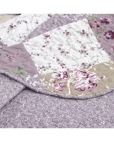 Close-up van een bloemen sprei, met een patchwork lavendelprint met een verfijnde stikstructuur. Close-up van een bloemen sprei, met een patchwork lavendelprint met een verfijnde stikstructuur.