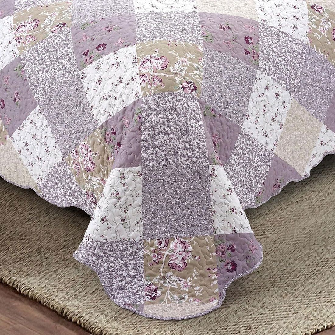 Detail of a floral quilt showcasing a patchwork lavender print, vermicelli stitching and scalloped edging. Detail of a floral quilt showcasing a patchwork lavender print, vermicelli stitching and scalloped edging.