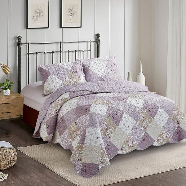 Een gezellige slaapkamer met een lavendelkleurig patchwork bloemen sprei en bijpassende kussens op een ijzeren bed.