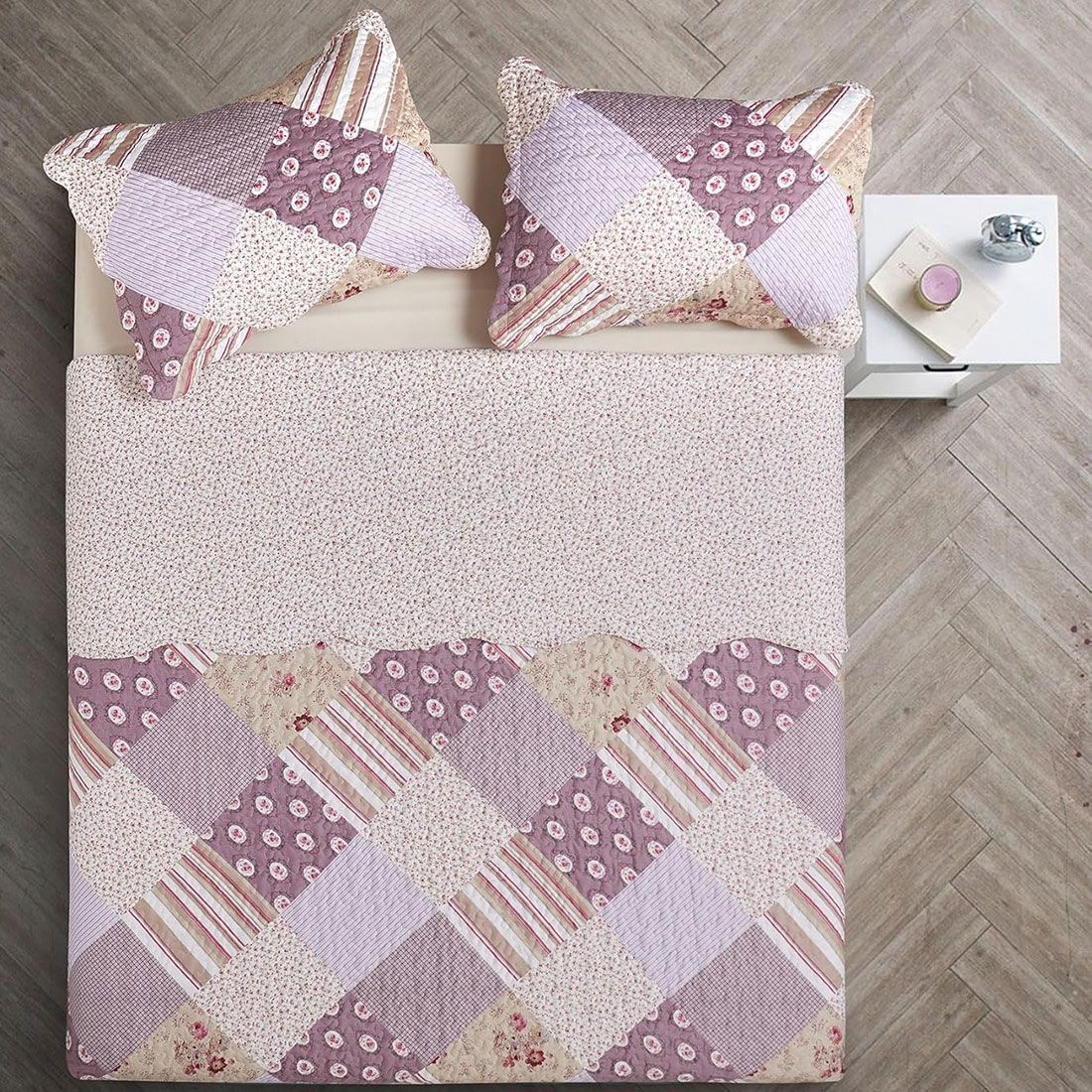 Top view of a patchwork quilt on a bed, complemented by matching decorative pillows. Top view of a patchwork quilt on a bed, complemented by matching decorative pillows.
