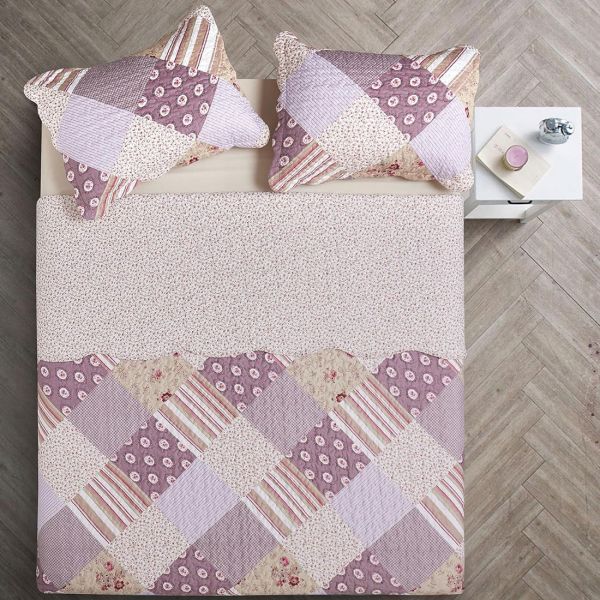 Bovenaanzicht van een bedsprei oud roze in patchwork op een bed, aangevuld met bijpassende sierkussens.