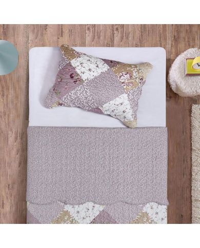 Top view of a lavender floral pillowcase on a bed, complemented by a matching patchwork quilt.