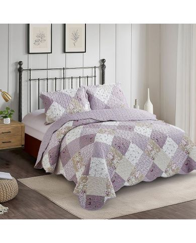 A cosy bedroom featuring a Lavender Dream patchwork quilt and matching pillowcases on an iron bed.