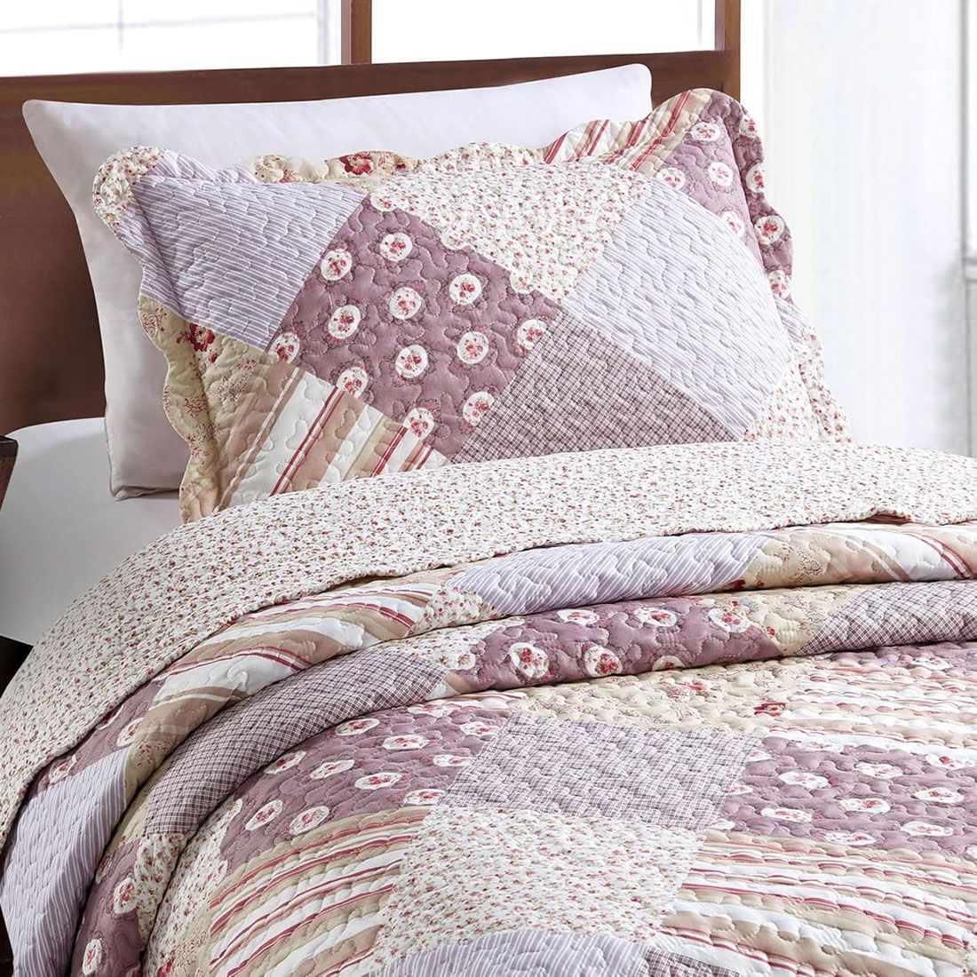 A pink pillowcase that combines floral, stripe, and check patch tiles with matching quilt on a cosy bed.