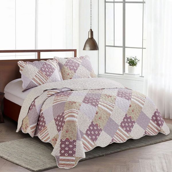 Een knus bed met daarop een patchwork bedsprei oud roze en mauve getint, aangevuld met bijpassende kussensloop roze.