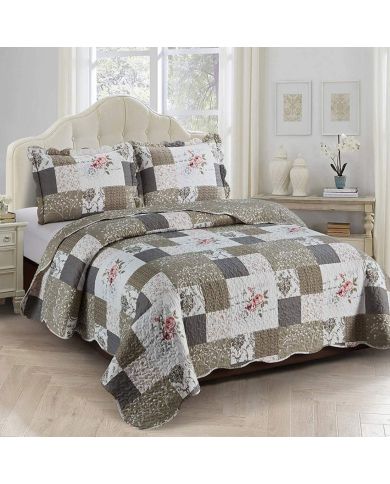 Beige patchwork quilt with a floral motif on a bed in a brightly decorated room.