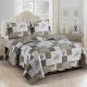 Beige patchwork quilt with a floral motif on a bed in a brightly decorated room.