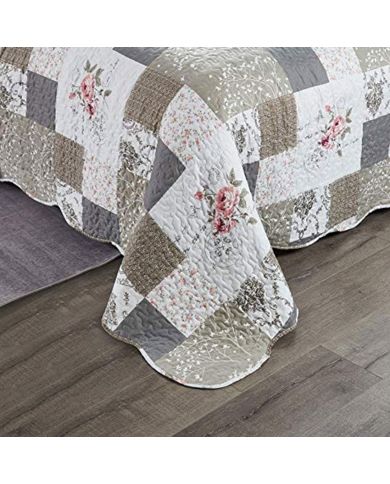 A patchwork quilt in beige and khaki featuring floral patterns, vermicelli stitching and scalloped edging. A patchwork quilt in beige and khaki featuring floral patterns, vermicelli stitching and scalloped edging.
