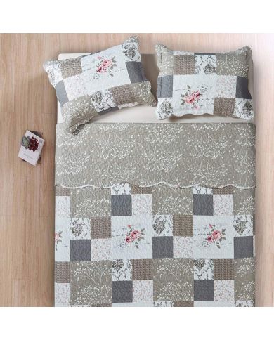 Bedsprei beige en wit gekleurd, met een gebloemd patchworkmotief, daarrbij een bijpassende sierkussens.