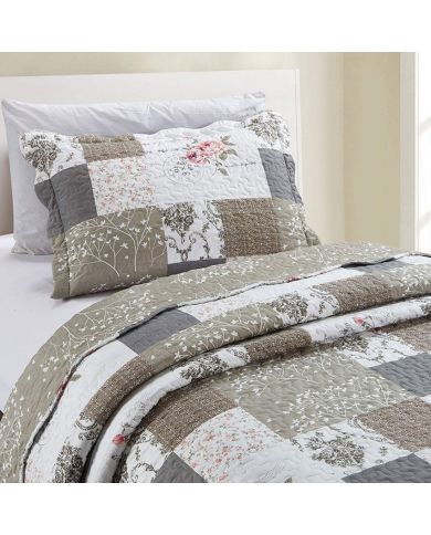 Een gezellige bedsprei beige en wit gekleurd, met bloemen- en patchworkmotieven, daarbij een bijpassend kussen.