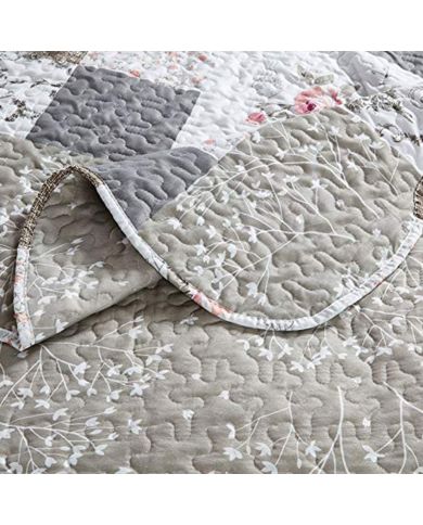 Close-up van een bedsprei beige en wit gekleurd, met bloemen en patronen en fijne stikselstructuur. Close-up van een bedsprei beige en wit gekleurd, met bloemen en patronen en fijne stikselstructuur.