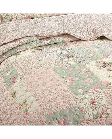 Close-up van een bedsprei bloemen motief, met roze en salie getint patchwork en fijne stikstructuur. Close-up van een bedsprei bloemen motief, met roze en salie getint patchwork en fijne stikstructuur.