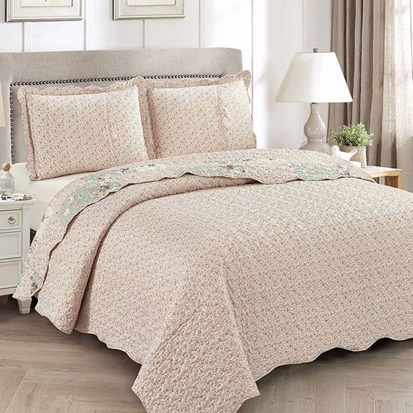 Showcasing the reverse design of the floral bedspread, a delicate rosebud print, paired with matching pillows.