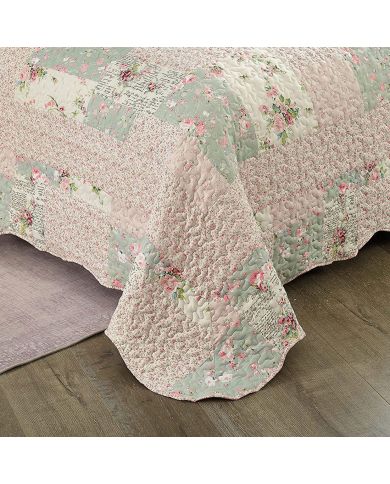 Detail van een bedsprei bloemen motief met roze en salie getint patchwork, vermicellistiksels en geschulpte randen.
