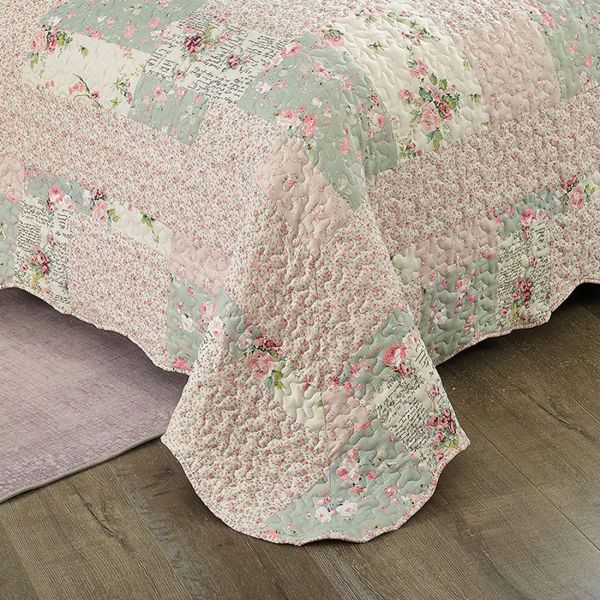 Detail van een bedsprei bloemen motief met roze en salie getint patchwork, vermicellistiksels en geschulpte randen.