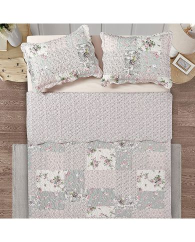 Bovenaanzicht van een bedsprei bloemen motief op een bed, aangevuld met bijpassende sierkussens.