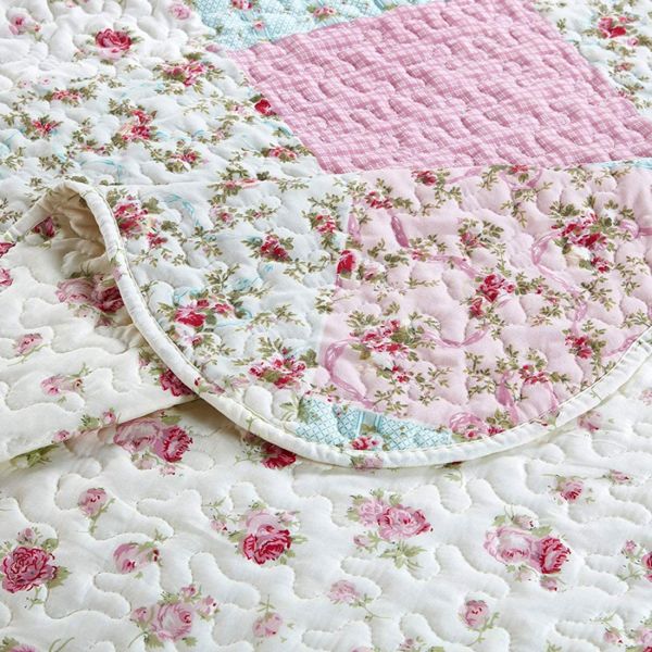 Close-up van een bedsprei roze patchwork en fijne stiksels.