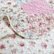 Close-up of a pink quilt, showcasing pink patchwork with a delicate stitching texture.