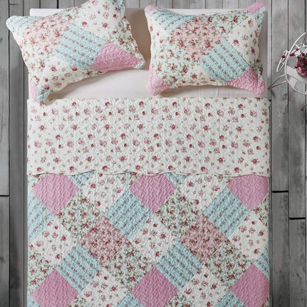 Top view of a patchwork pink quilt on a bed, complemented by matching decorative pillows.