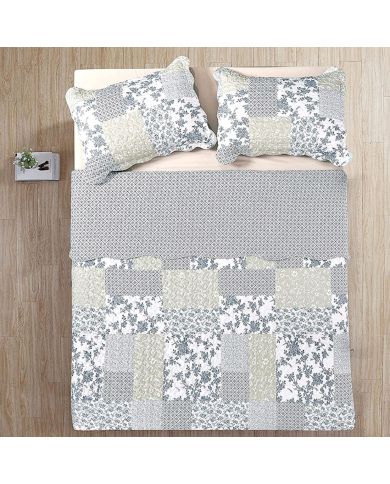 Bovenaanzicht van een patchwork bedsprei blauw, op een bed, aangevuld met bijpassende sierkussens.