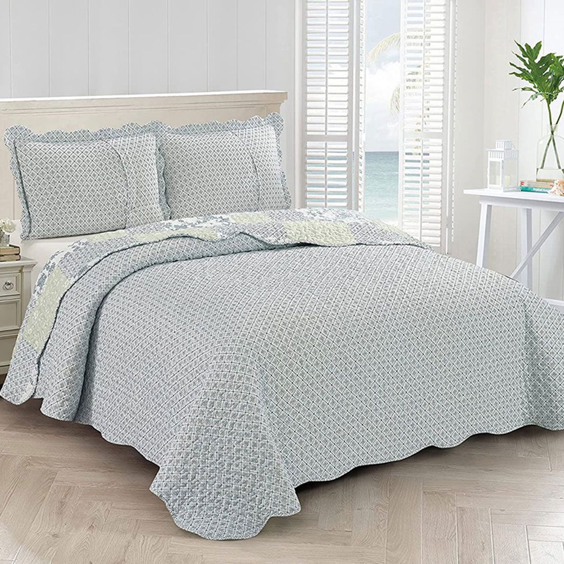 Showcasing the reverse design of the blue quilt, a diamond pattern with a small floral print, paired with matching pillows. Showcasing the reverse design of the blue quilt, a diamond pattern with a small floral print, paired with matching pillows.