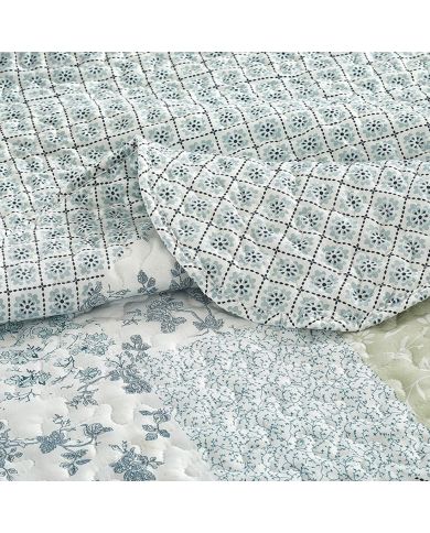 Close-up van een bedsprei blauw en groene tinten met een verfijnd stiksel. Close-up van een bedsprei blauw en groene tinten met een verfijnd stiksel.