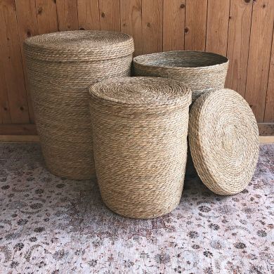 A group of laundry baskets with lids in assorted sizes sits on a Persian carpet.