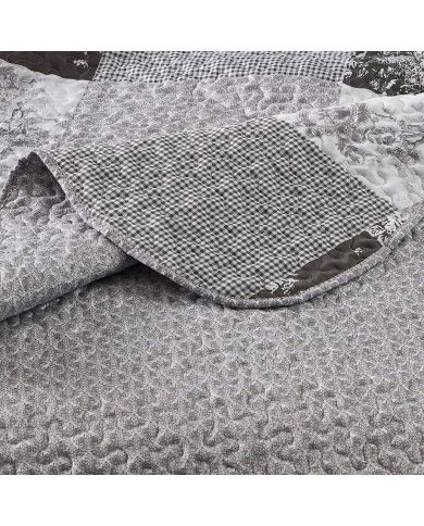 Close-up of a grey quilt, showcasing a small grey floral toile pattern with a delicate stitching texture. Close-up of a grey quilt, showcasing a small grey floral toile pattern with a delicate stitching texture.