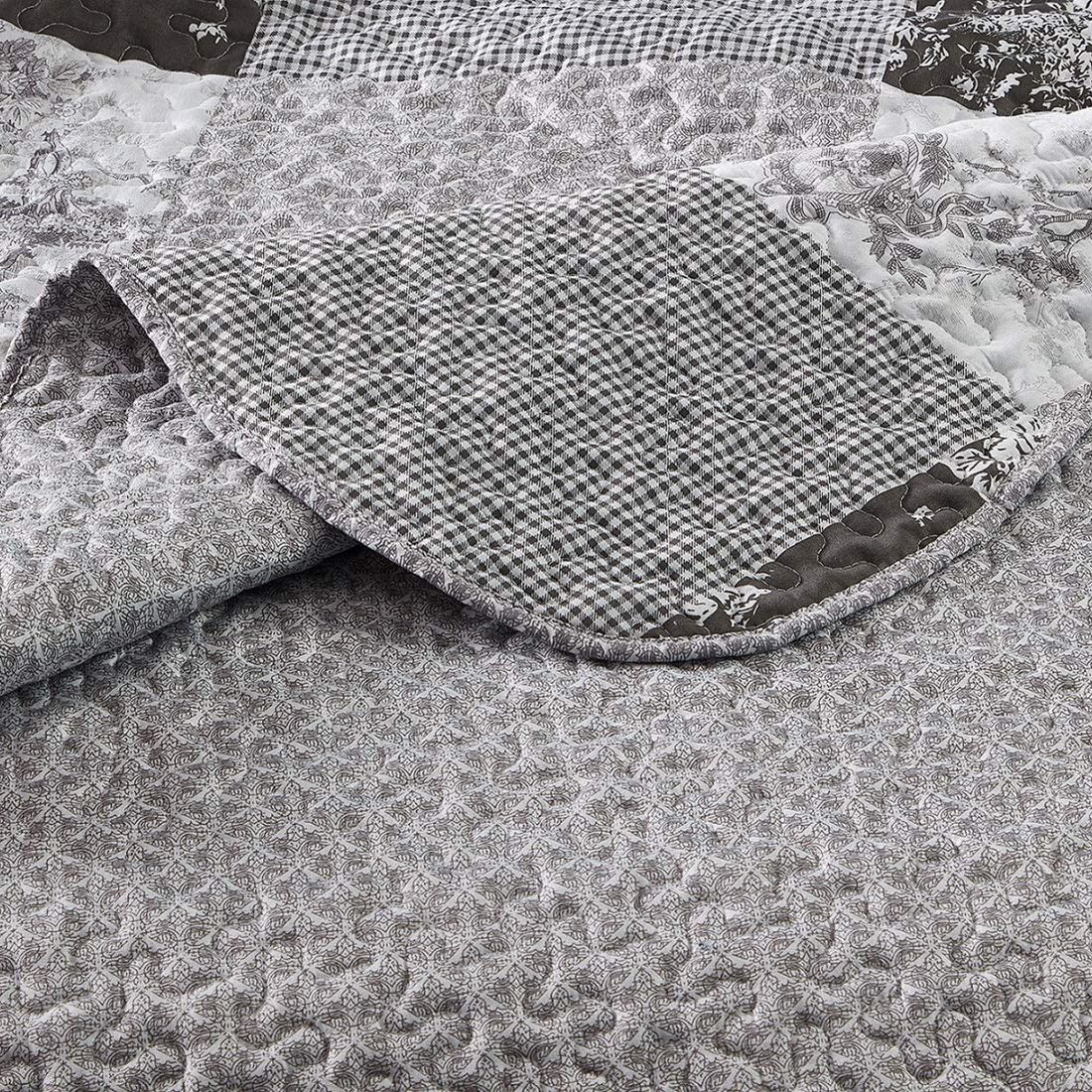 Close-up of a grey quilt, showcasing a small grey floral toile pattern with a delicate stitching texture. Close-up of a grey quilt, showcasing a small grey floral toile pattern with a delicate stitching texture.