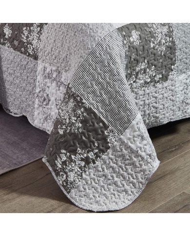 Detail van een grijze bedsprei met toile-bloempatroon, vermicelli-stiksel en schulprand.