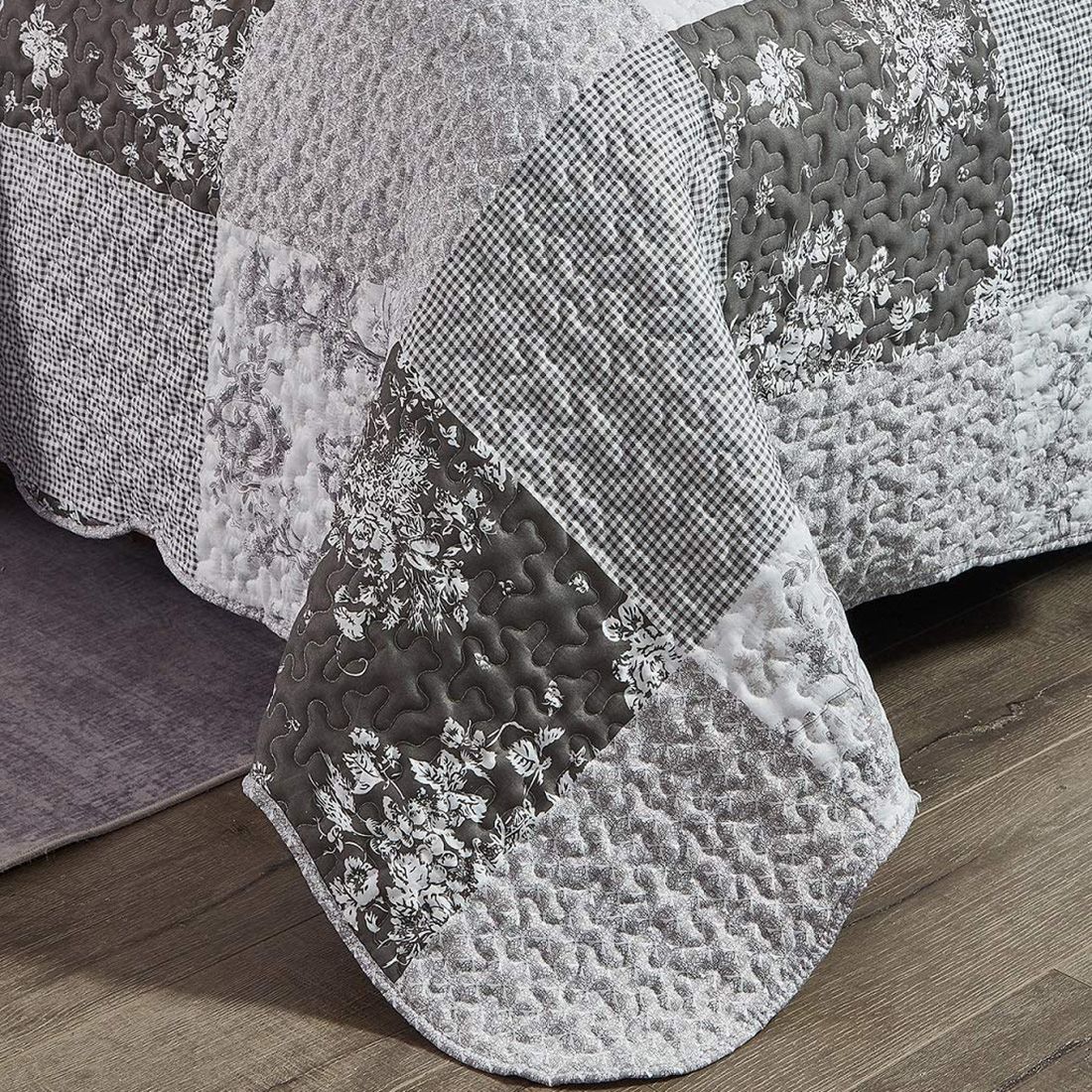 Detail of a grey quilt showcasing floral toile pattern, vermicelli stitching and scalloped edging. Detail of a grey quilt showcasing floral toile pattern, vermicelli stitching and scalloped edging.