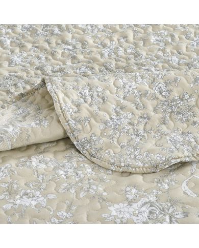 Close-up van een beige bedsprei met een toile-bloempatroon en fijne stiksels. Close-up van een beige bedsprei met een toile-bloempatroon en fijne stiksels.