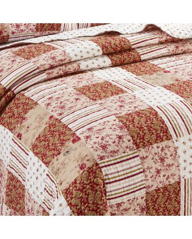 Close-up van een roze bedsprei met een symfonie van gedempt roze en cranberry vlakken.