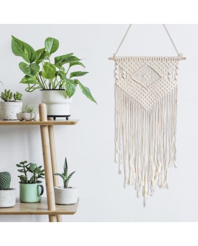 A macramé wall hanging with fringe hangs next to a wooden shelf filled with potted plants. A macramé wall hanging with fringe hangs next to a wooden shelf filled with potted plants.