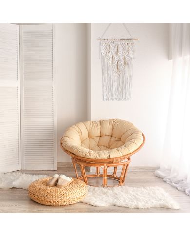 A cosy interior featuring a round rattan chair on a sheepskin rug with a room divider and a macramé wall hanging. A cosy interior featuring a round rattan chair on a sheepskin rug with a room divider and a macramé wall hanging.