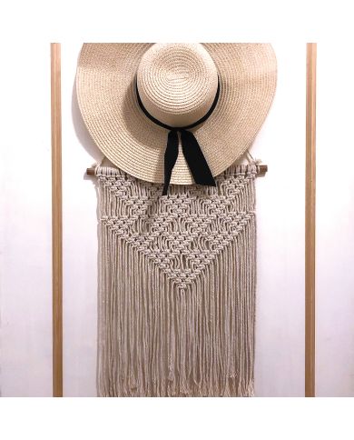 Een breedgerande strooien hoed met een zwart lint hangt over een macramé vintage wandhanger met gedetailleerde knoopontwerpen. Een breedgerande strooien hoed met een zwart lint hangt over een macramé vintage wandhanger met gedetailleerde knoopontwerpen.