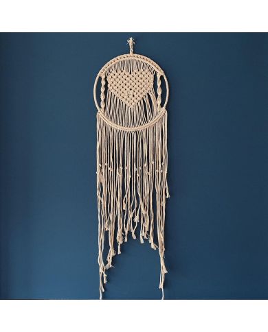 Macramé boho wandhanger in hartvorm met franjes, tegen een diepblauwe muur. Macramé boho wandhanger in hartvorm met franjes, tegen een diepblauwe muur.