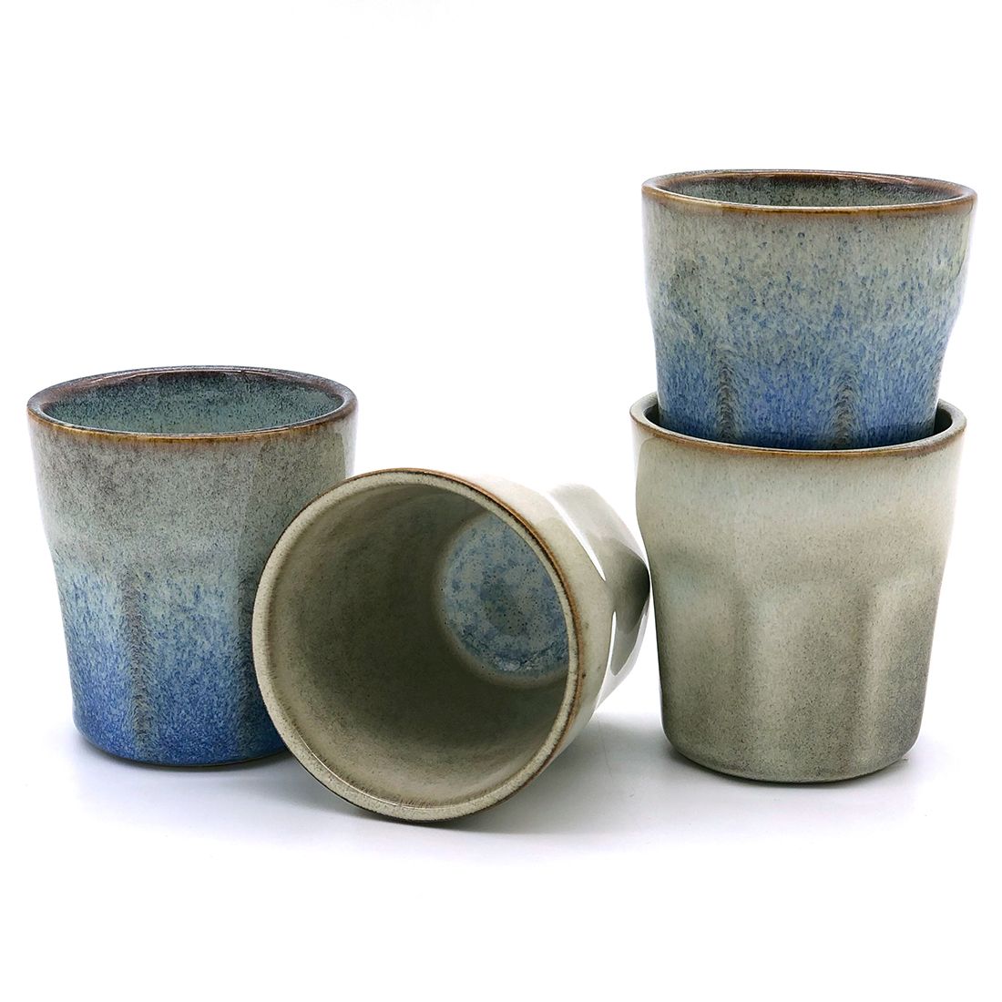 Four handmade espresso cups in varying shades of blue and grey, stacked and arranged artistically.