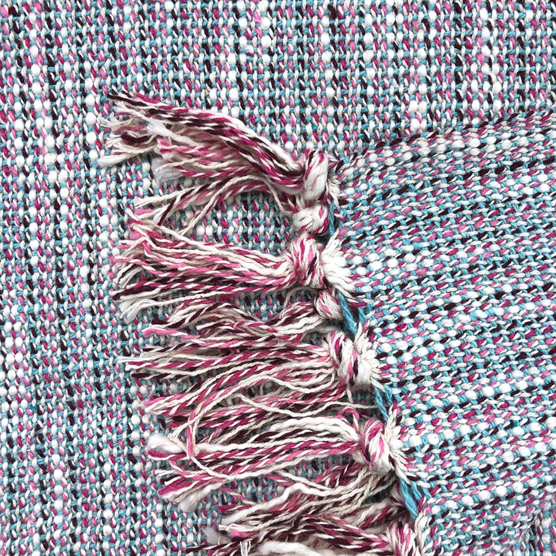 Close-up van een geweven katoenen plaid met kwastjes aan de randen.