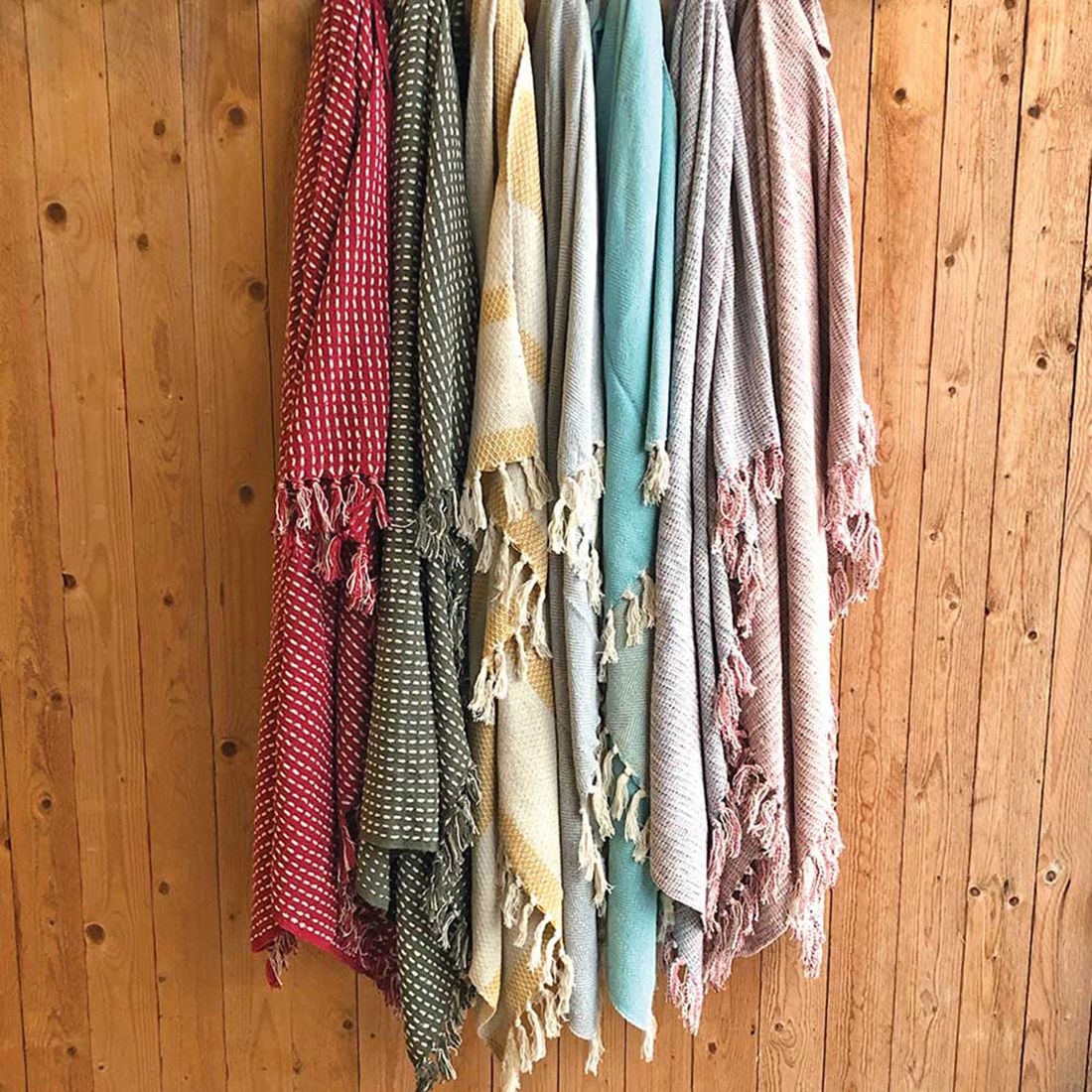 Verzameling van een kleurrijk geweven katoenen plaid tegen een houten muur.