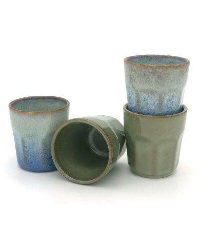 Four handmade espresso cups in varying shades of blue and green, stacked and arranged artistically.