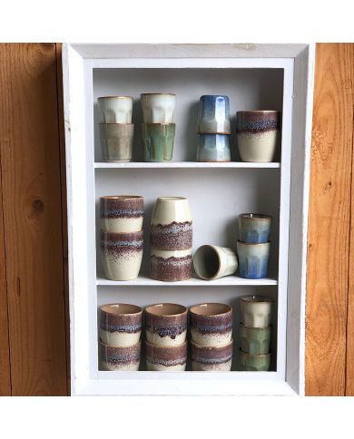A display of artistically arranged handmade espresso cups in soft hues of blue and green.